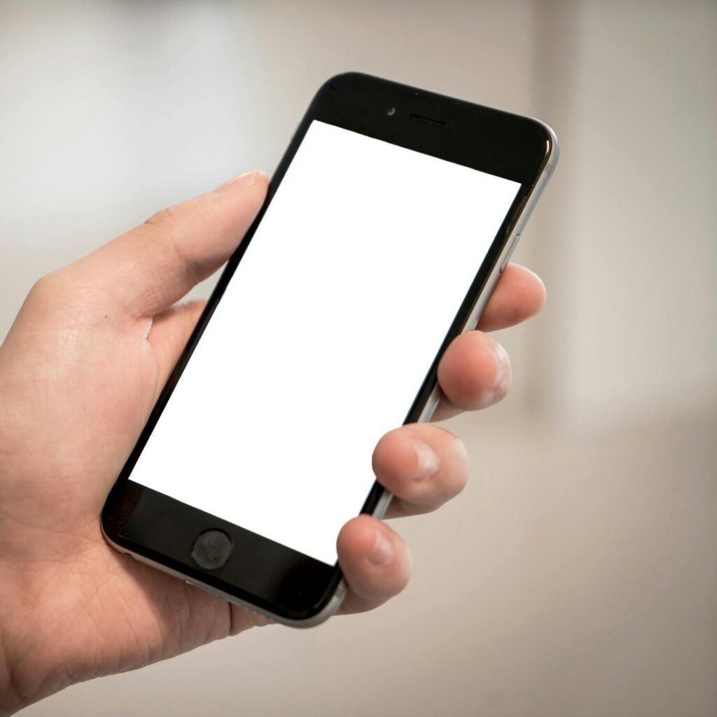 Selective Focus Photography of Person Holding Iphone Displaying White Screen